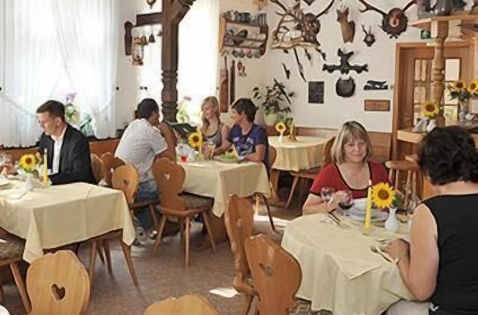 Un comedor con mesas redondas, sillas y girasoles sobre las mesas.