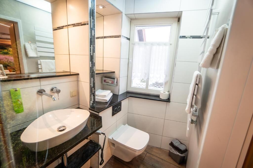 Une petite salle de bain avec un lavabo blanc, des toilettes et un miroir.