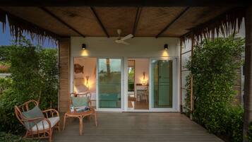 Um deck externo com móveis de vime, ventilador de teto e portas de vidro que dão para um quarto.