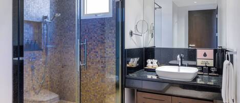 A modern bathroom with a glass-enclosed shower, a sink with a 'SAVE WATER' sign, and a large mirror.