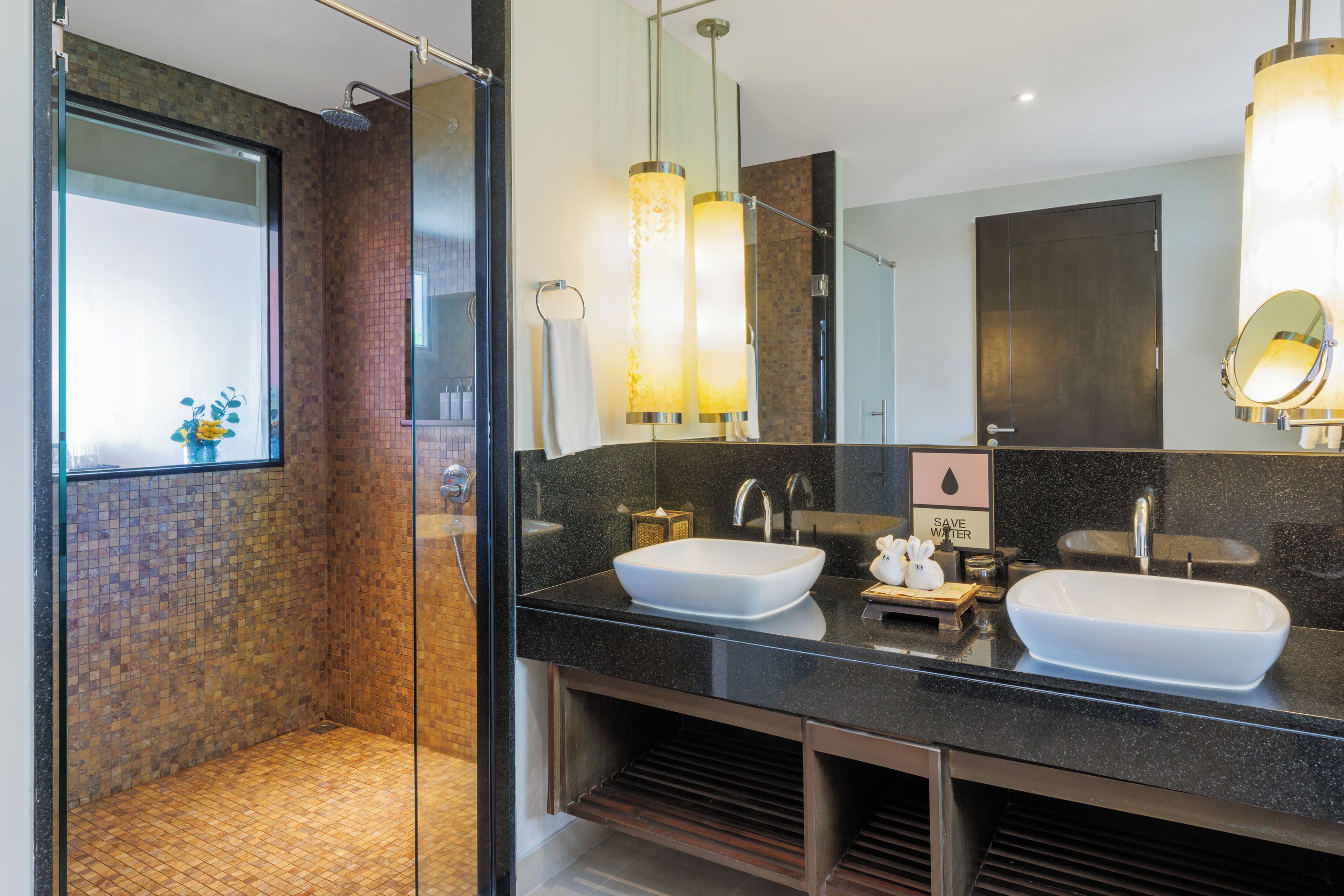 A modern bathroom with a glass-enclosed shower, two sinks, and a large mirror.