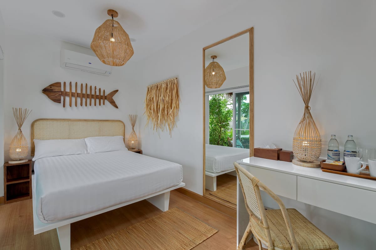 A bedroom with a bed, bedside tables, a desk, a chair, a large mirror, and decorative items.