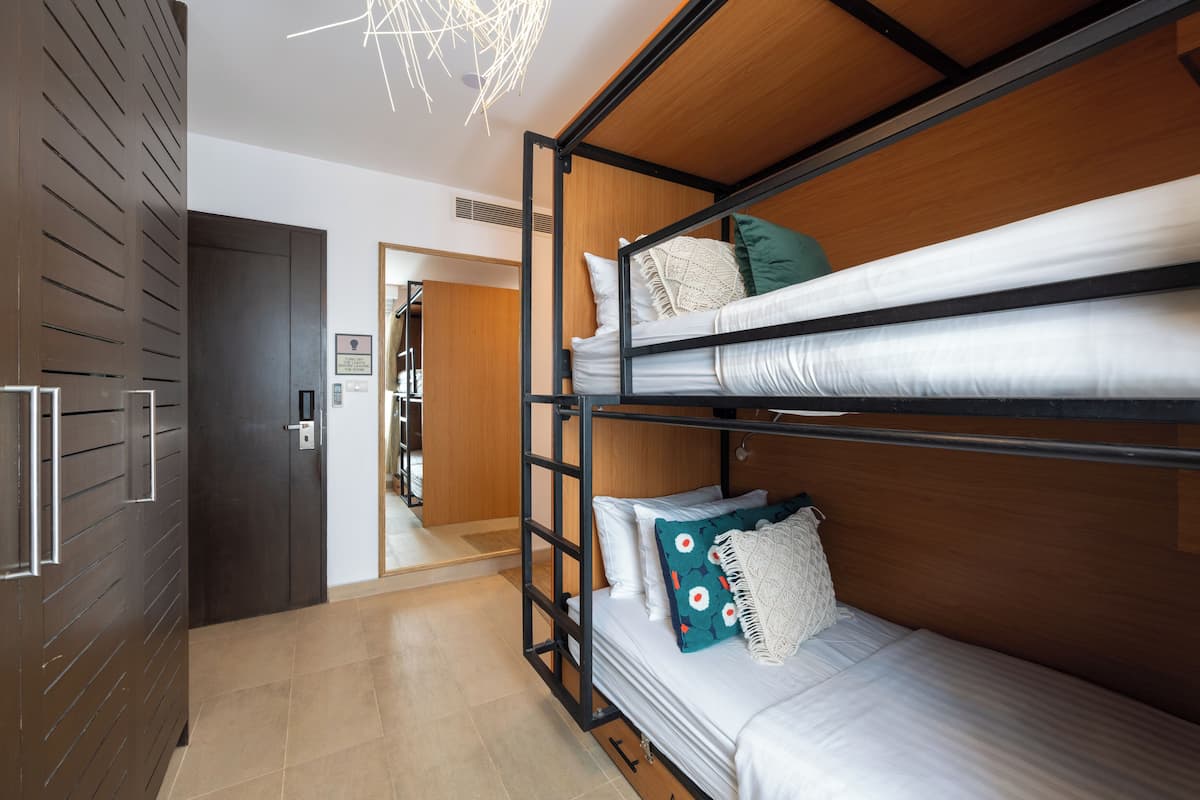 A bunk bed room with a wooden headboard, a door with a handle, and a light fixture on the ceiling.