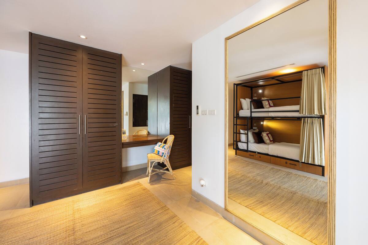 A bedroom with a bunk bed, a chair, and a wardrobe.