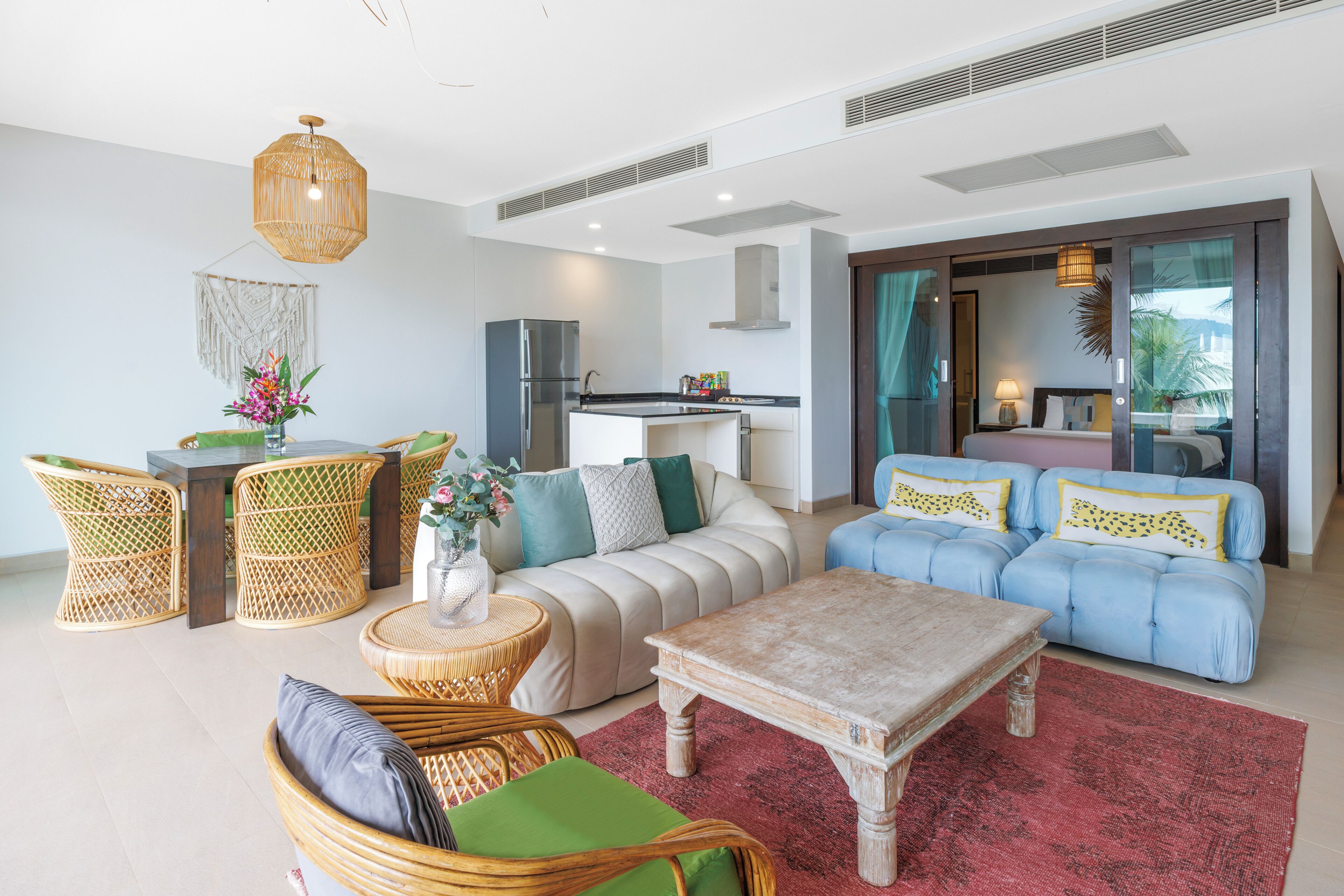A modern living room with a sofa, chairs, a coffee table, and a kitchen area.
