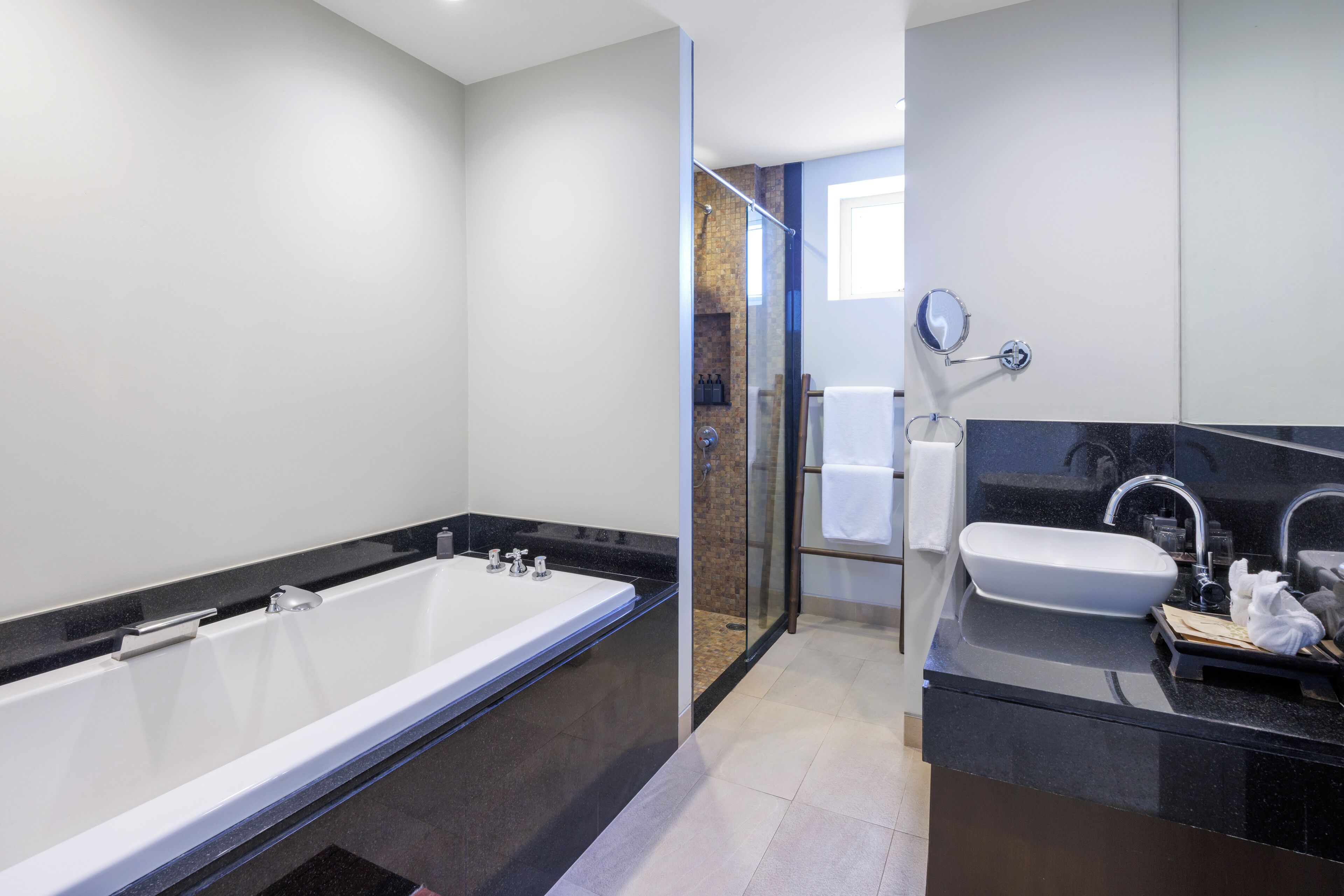 A modern bathroom with a large bathtub, a separate sink, and a glass shower enclosure.