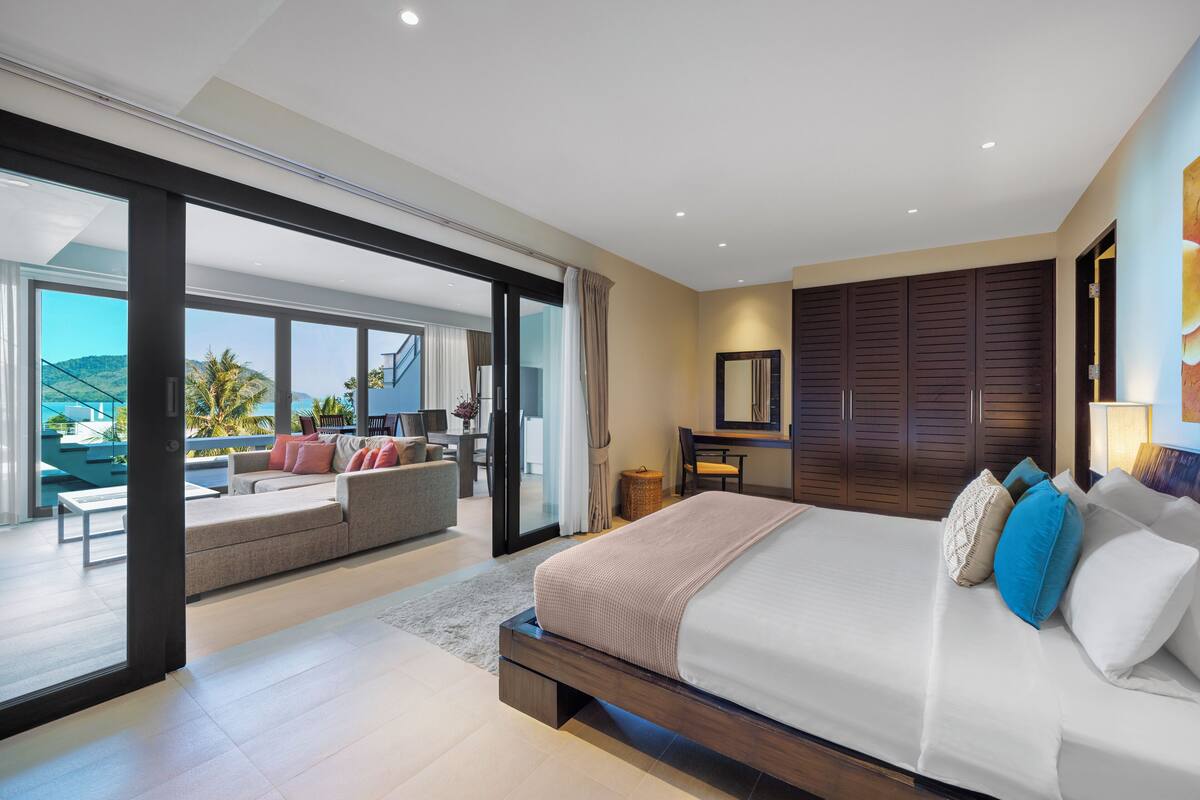 A modern bedroom with a large bed, a sofa, a desk, and a wardrobe.