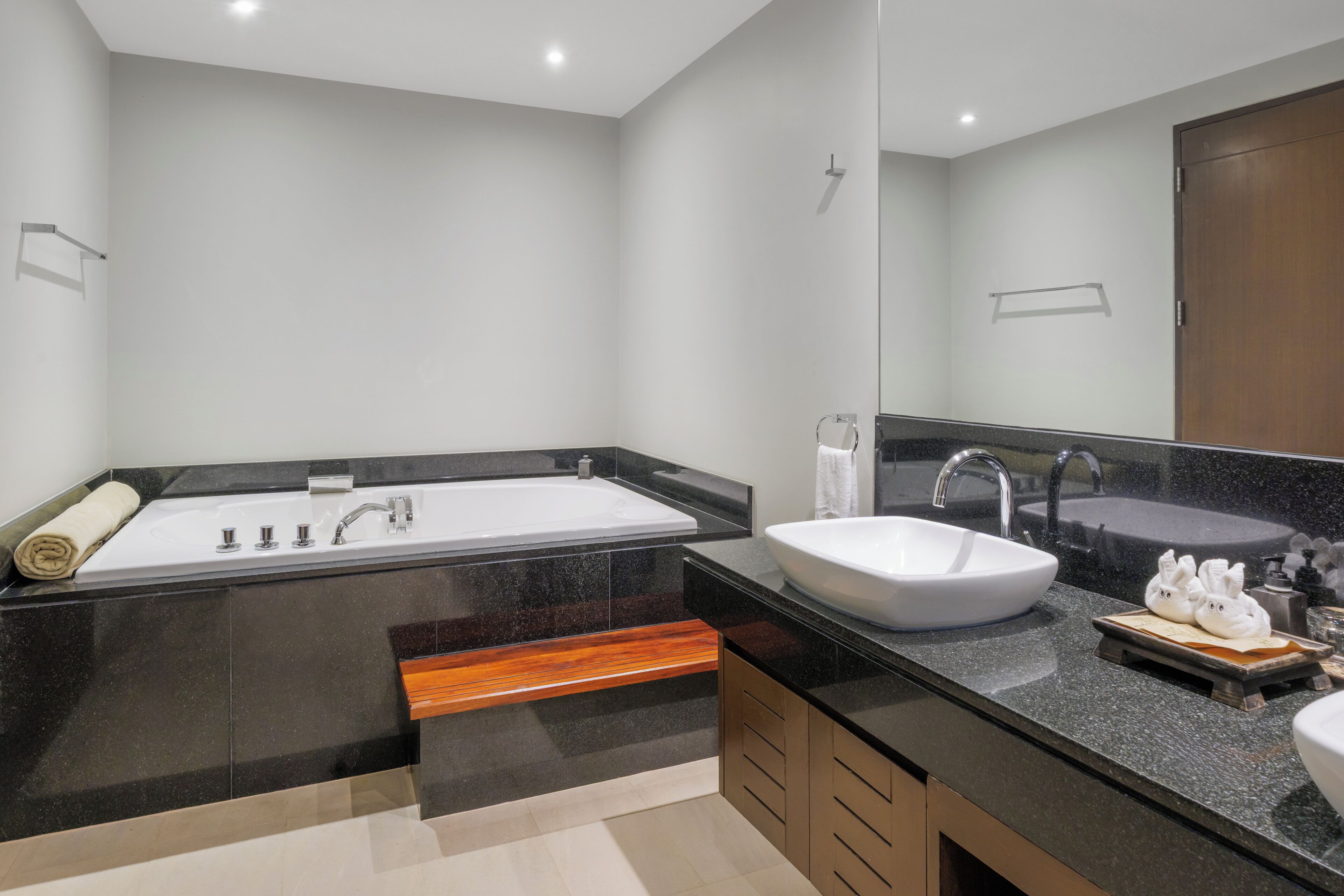 A modern bathroom with a large bathtub, a sink, and a mirror.