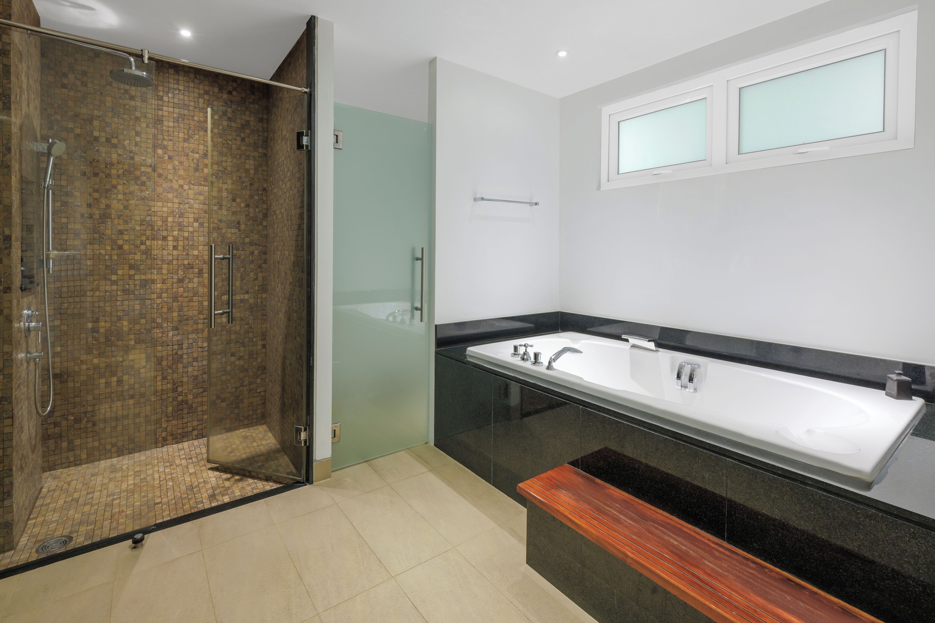 Une salle de bain moderne avec une douche à parois de verre, une grande baignoire et un banc en bois.