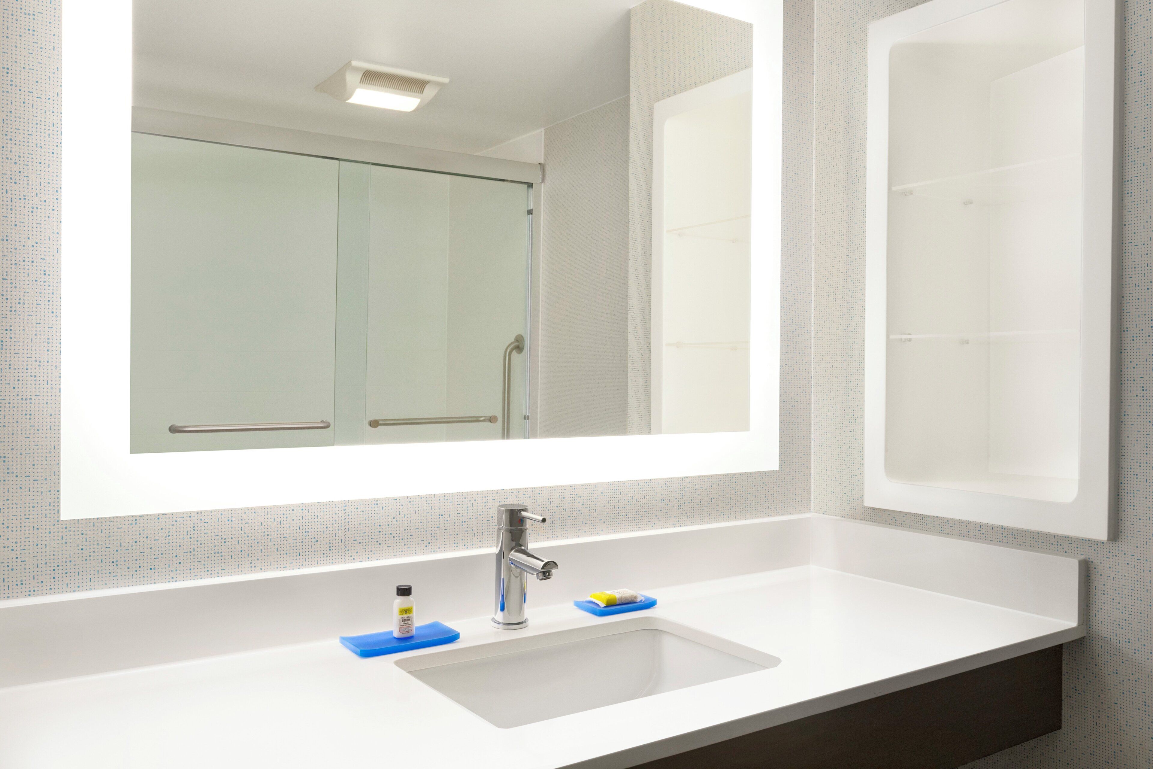 Un baño con un espejo grande, un lavabo y una zona de ducha.