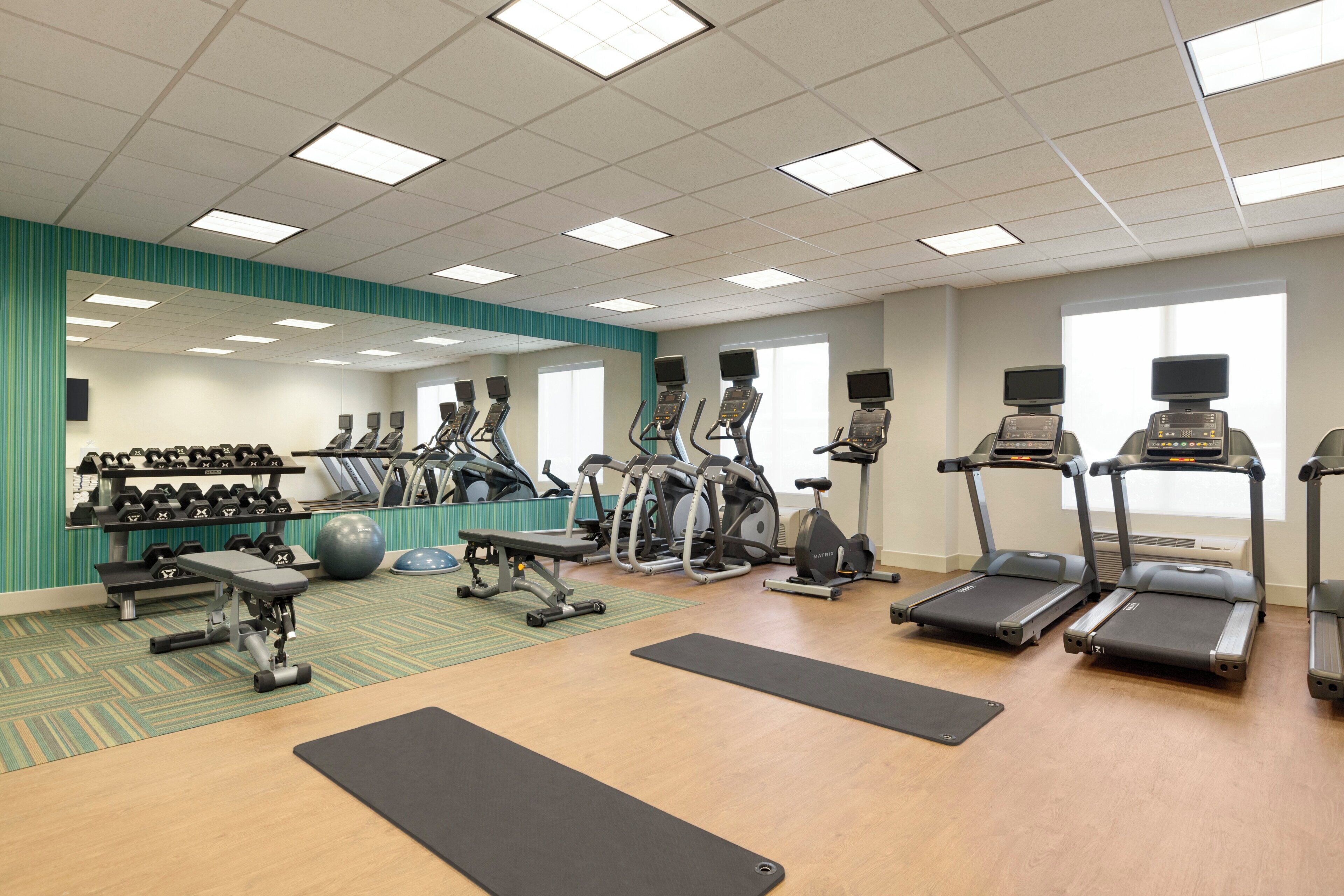 A gym with treadmills, elliptical machines, and free weights.
