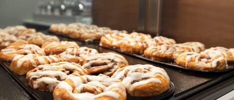 A tray of cinnamon rolls with icing on a black surface.