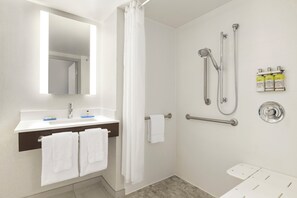 Een moderne badkamer met een douche, een wastafel en een spiegel.