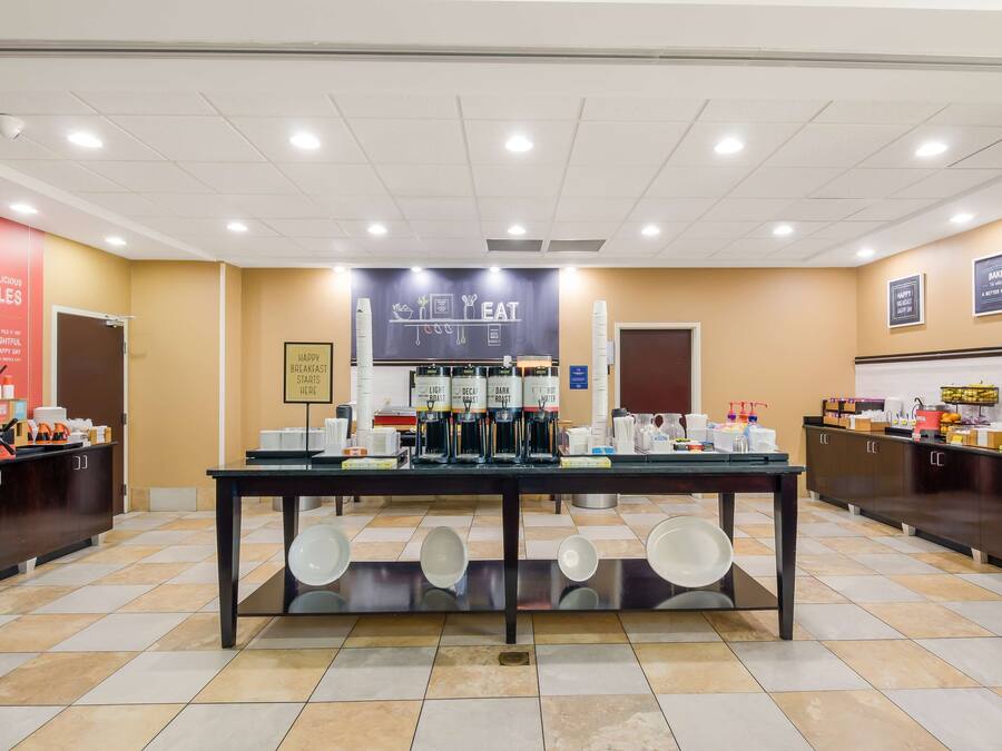A breakfast buffet area with a counter displaying various coffee options and a sign above stating "Happy Breakfast Here".