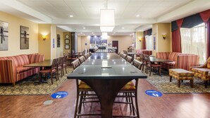 A spacious hotel lobby with a long conference table, multiple seating areas, and a clock on the wall. - Hampton Inn Galax (Galax)