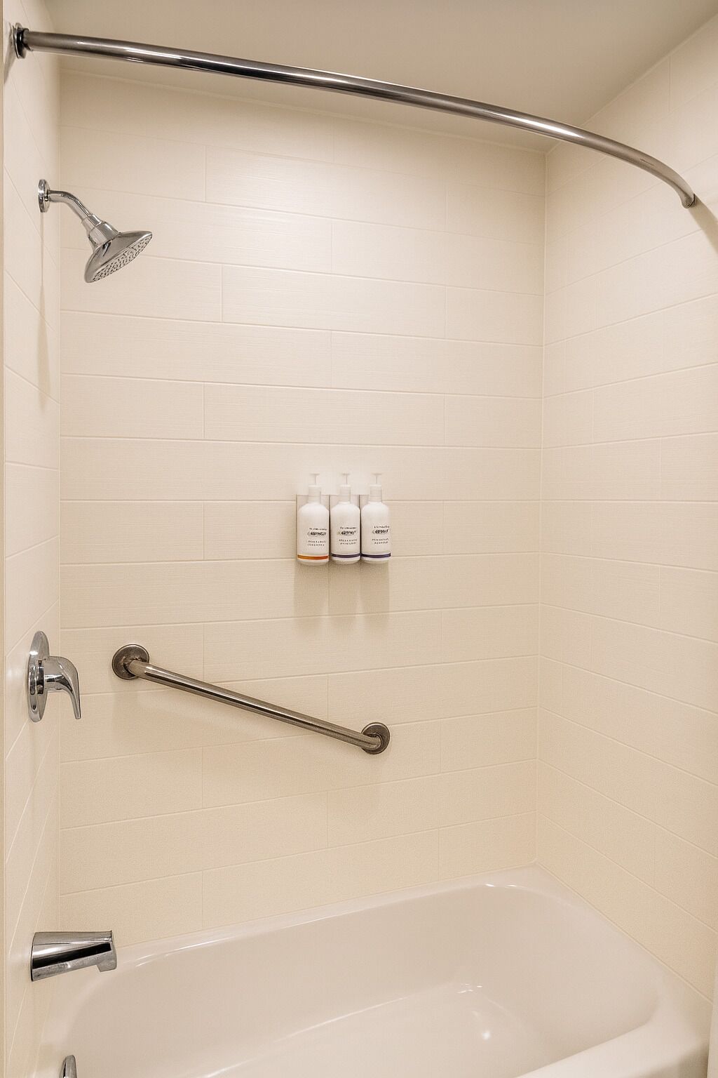 A bathroom with a bathtub, a shower, and a grab bar.