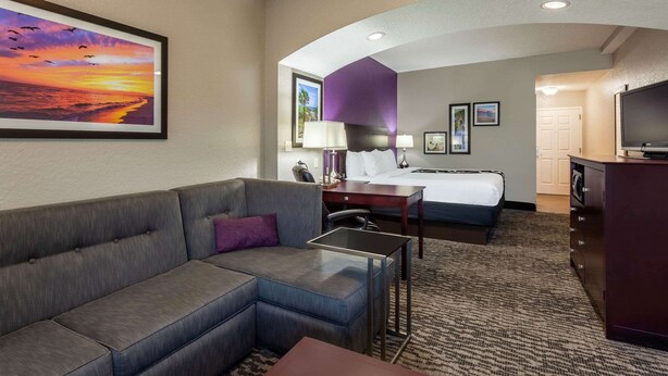 A hotel room with a sofa, a bed, a desk, and a TV.