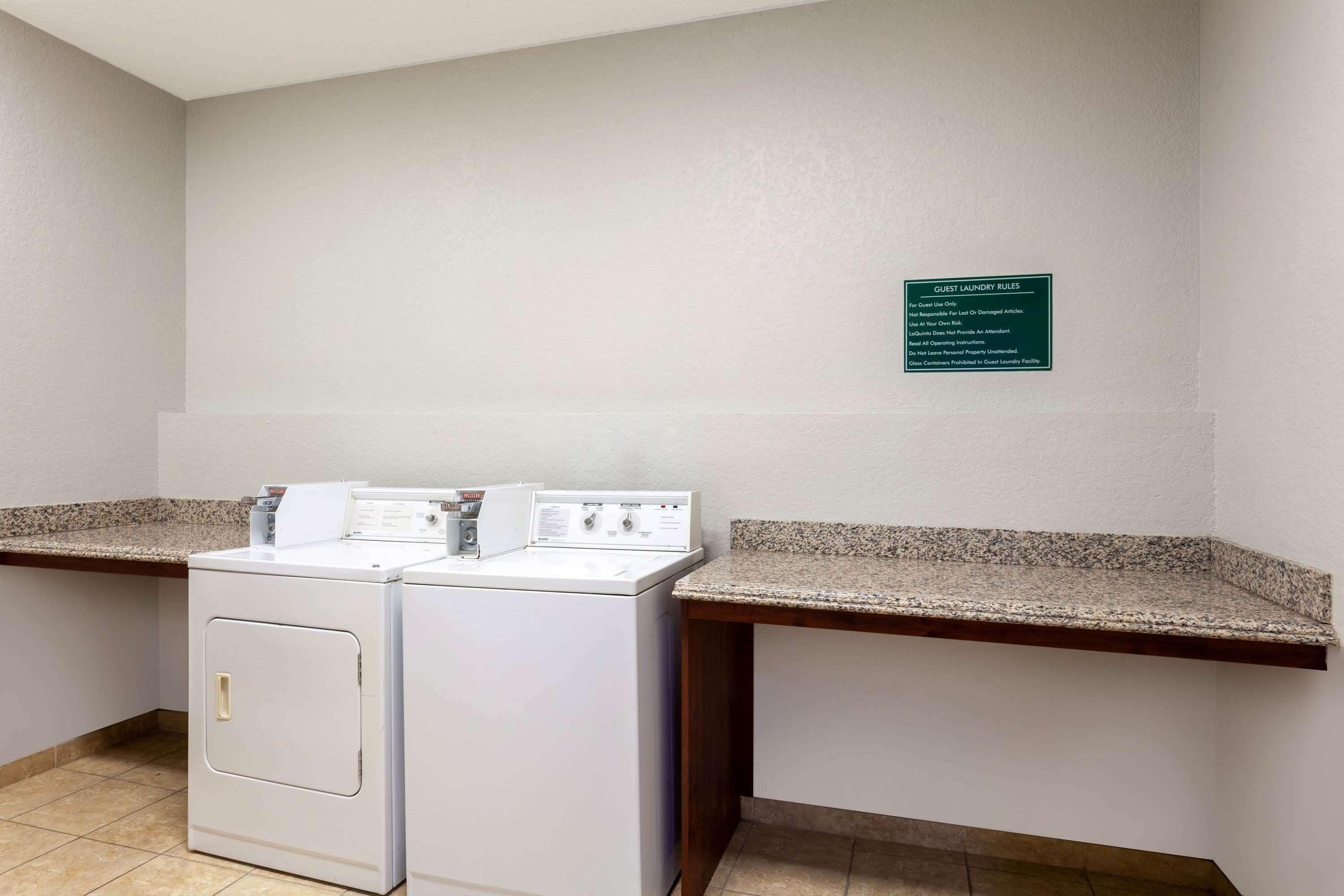 A laundry room with two washing machines and a sign detailing guest laundry rules.