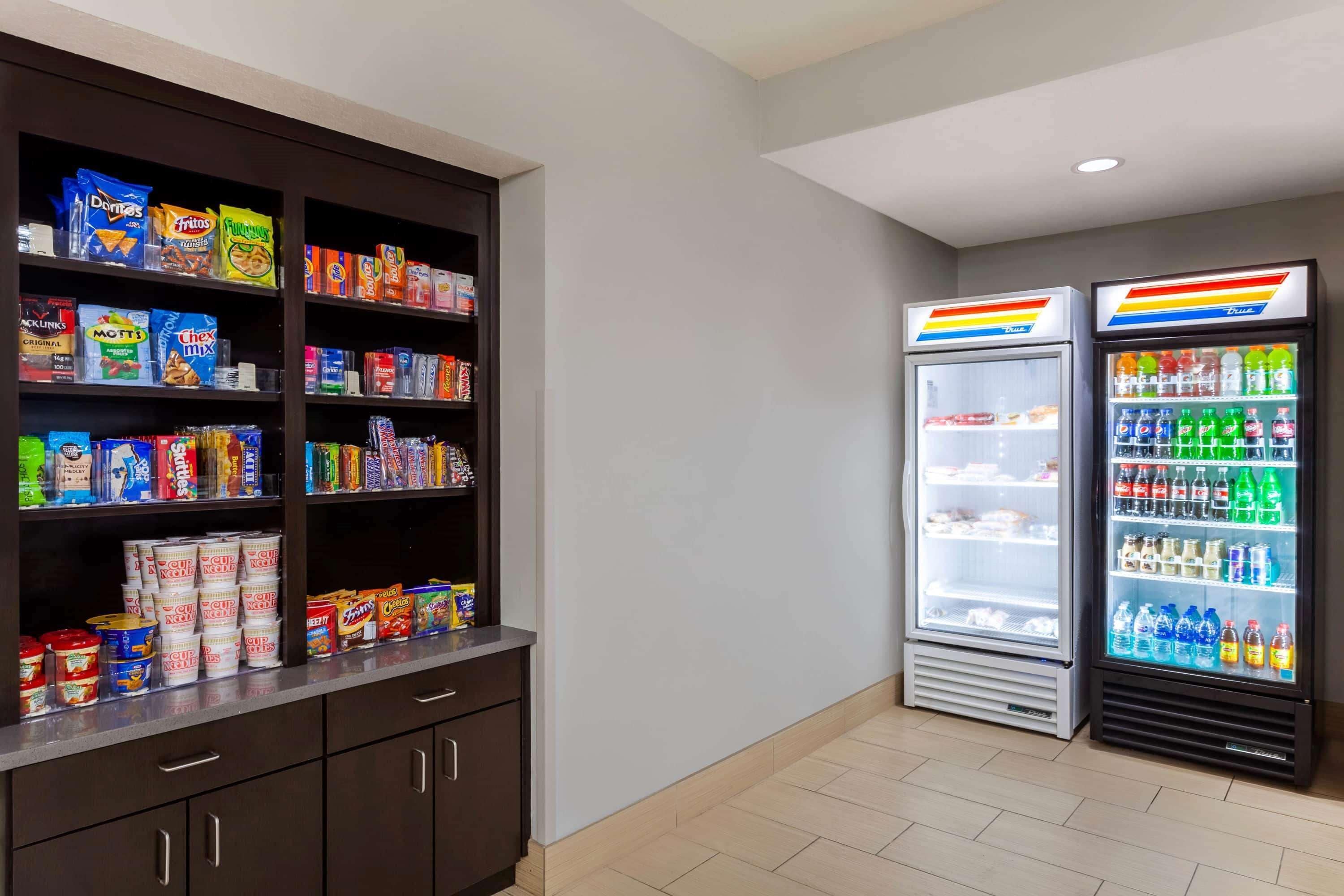 A snack and beverage area with shelves stocked with various snacks and two refrigerated beverage dispensers.