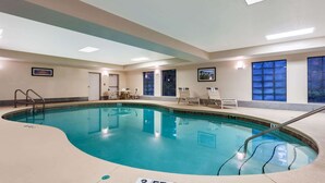 An indoor swimming pool with clear water, a tiled deck, and lounge chairs.