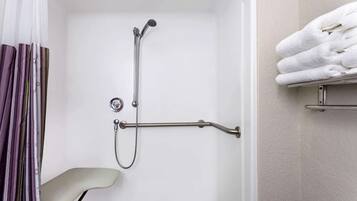 A shower area with a handheld showerhead, a grab bar, and a towel rack.