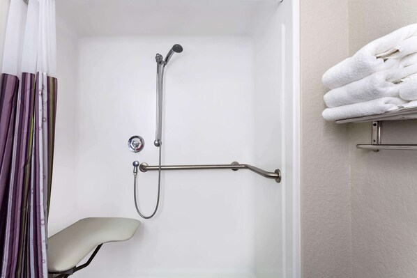 A shower area with a handheld showerhead, a grab bar, and a towel rack.