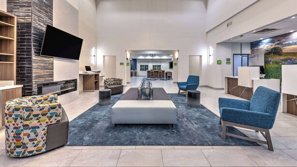 A spacious lobby with a modern fireplace, a flat-screen TV, comfortable seating, and a view into the dining area.