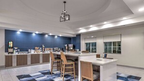 A modern kitchen with a central island, bar stools, and a blue backsplash.