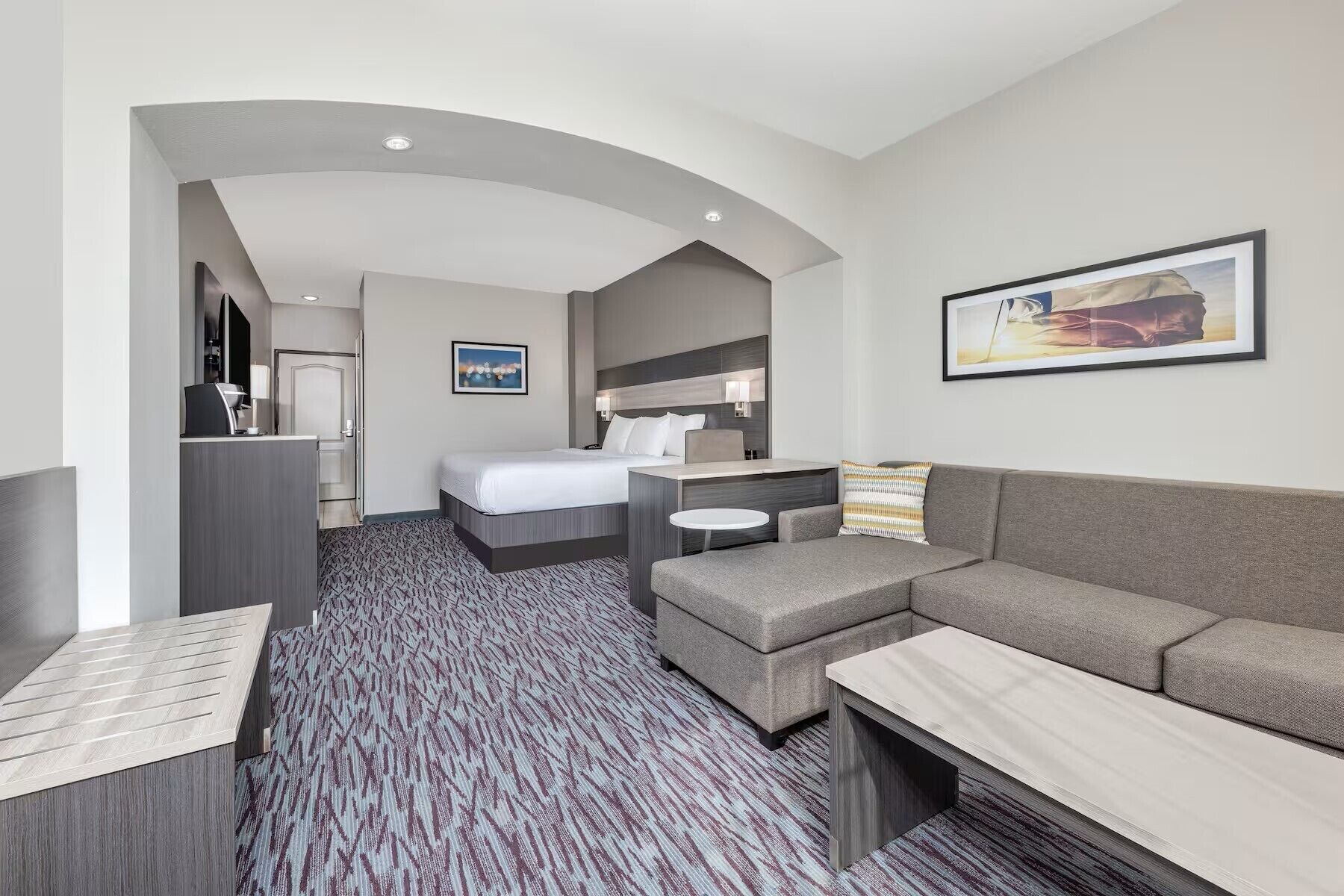 A hotel room with a bed, a sofa, a desk, and a small table.