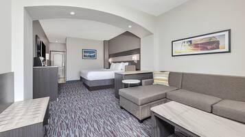 A hotel room with a bed, a sofa, a desk, and a small table.