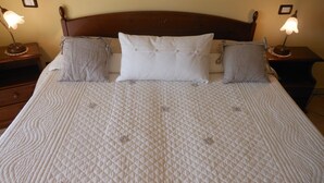 A neatly made bed with a quilted white bedspread, flanked by two bedside tables with lamps, and a wooden headboard. - Ca D Gnese (Castagnole delle Lanze)