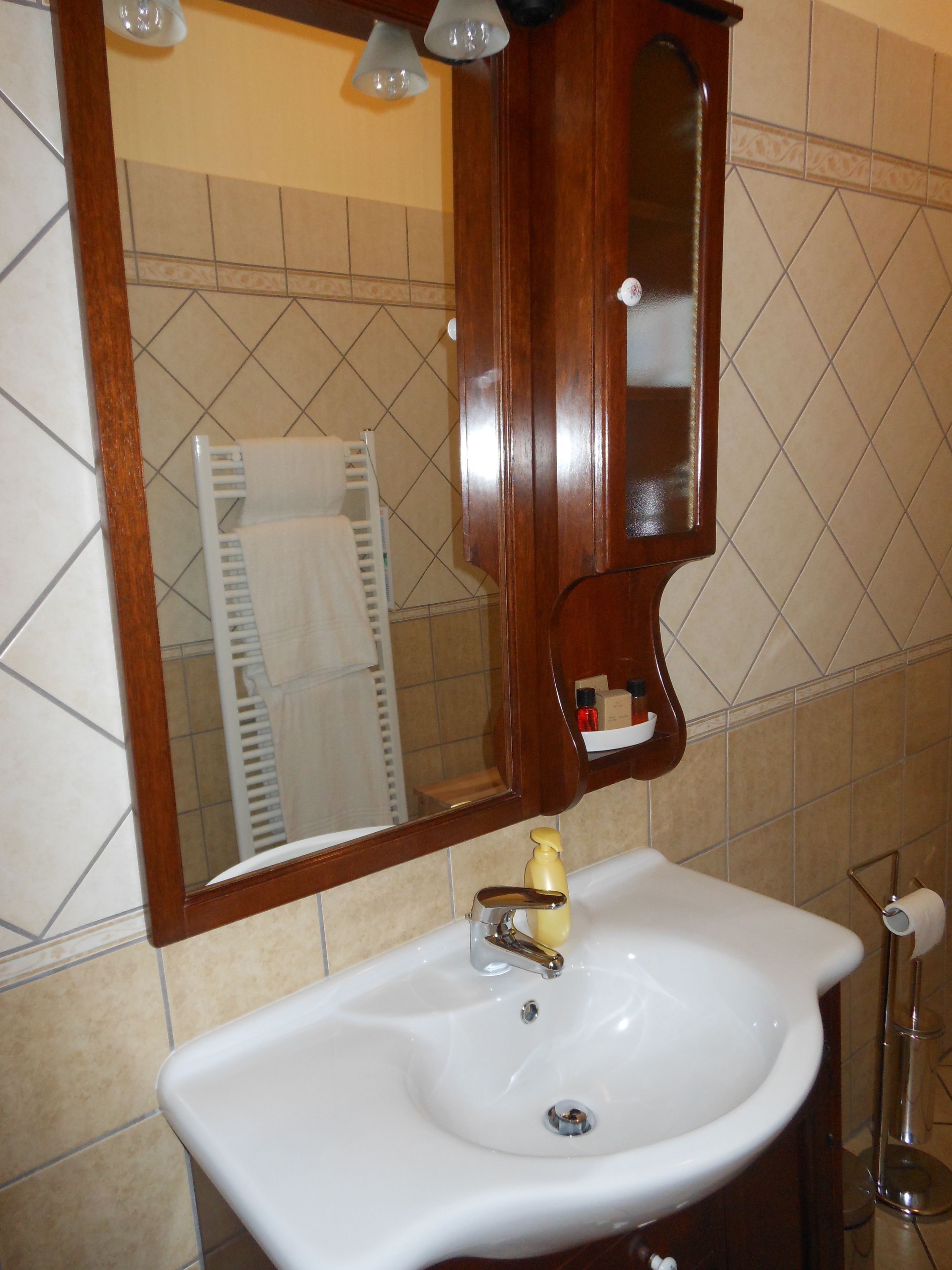 A bathroom with a white sink, a wooden cabinet, and a mirror.