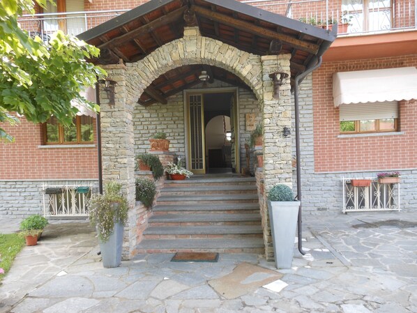 Un arco de piedra que conduce a la entrada de un edificio, con escalones y plantas en macetas.