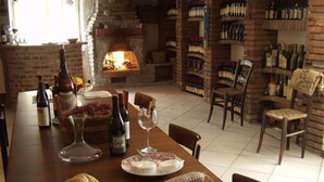 A dining area with a brick fireplace, a wine rack, and a table set with bread, cheese, and wine glasses. - Ca D Gnese (Castagnole delle Lanze)