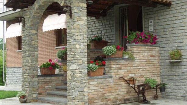 A stone building with a tiled roof, a porch with steps, and potted plants. - Ca D Gnese (Castagnole delle Lanze)
