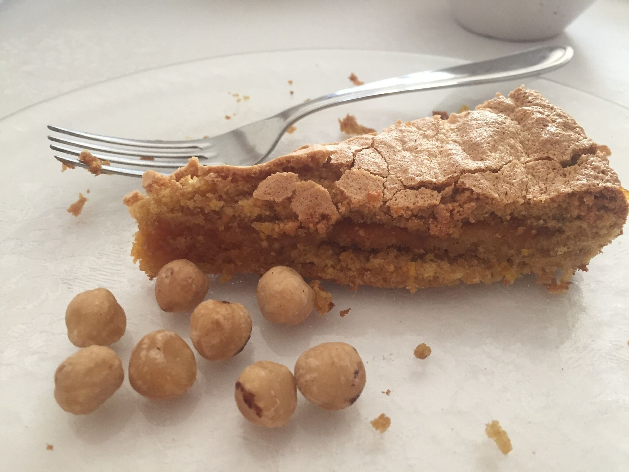 A slice of cake with crumbs and peanuts on a plate.
