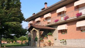A traditional brick building with multiple balconies, stone flooring, and potted plants. - Ca D Gnese (Castagnole delle Lanze)