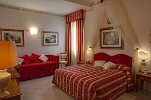 Ein Hotelzimmer mit einem Bett, einem roten Sofa, einem Nachttisch und Wandlampen.
