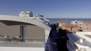 Un edificio moderno con un balcón curvo que da a una zona residencial y una vista despejada del mar.