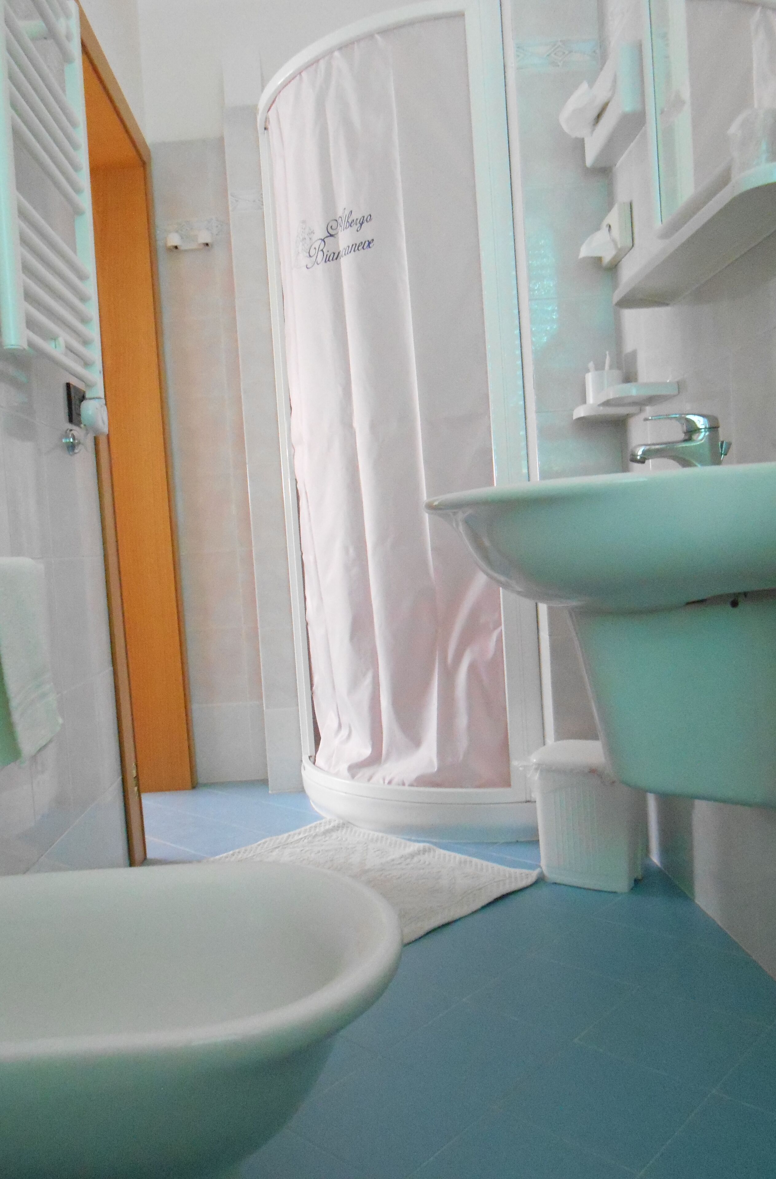 Ein Badezimmer mit einer weißen Badewanne, einem weißen Waschbecken und einem blauen Boden.