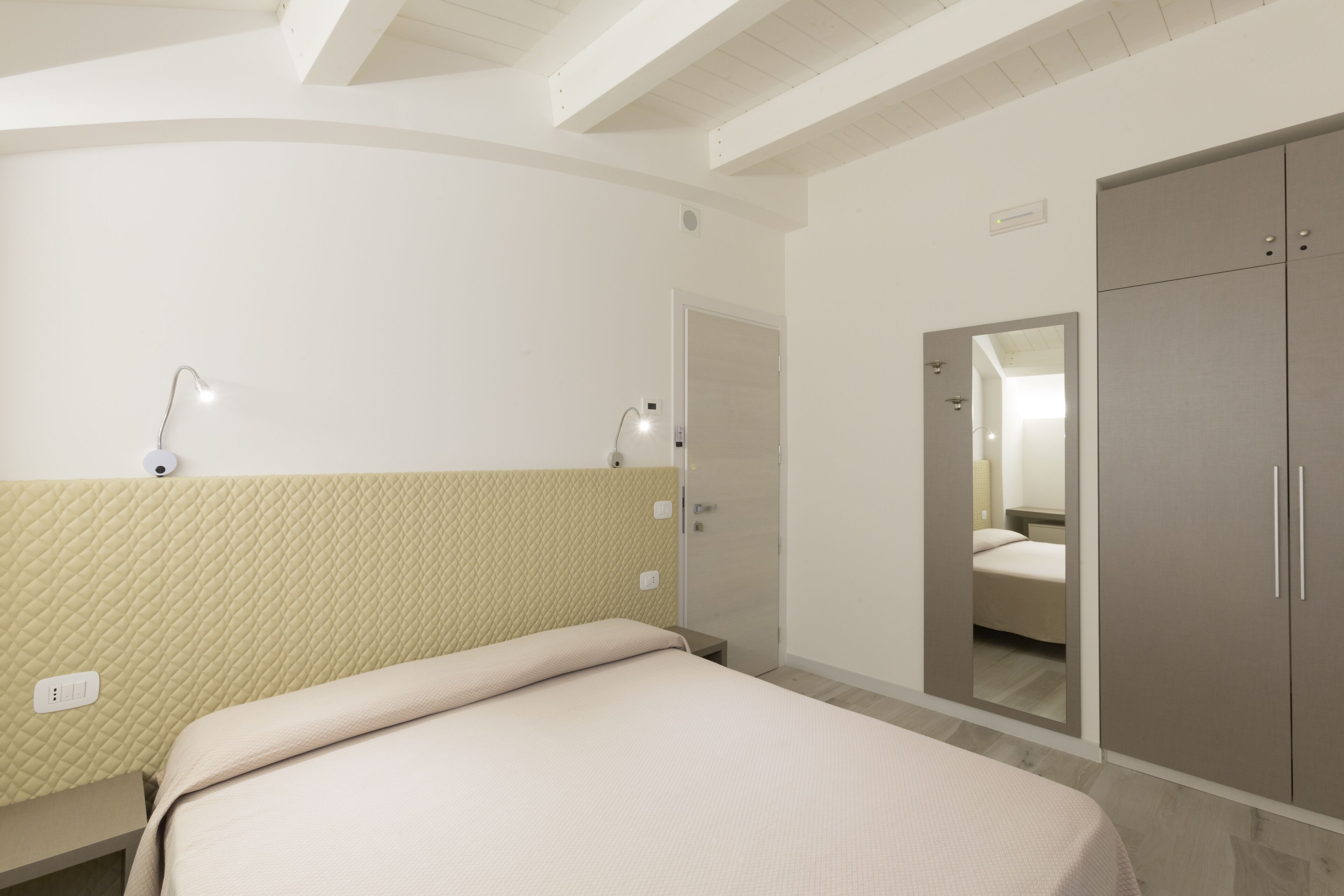 Een hotelkamer met een bed, een kledingkast en een spiegel.