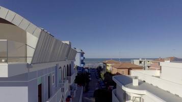 Una calle residencial con vista despejada al mar, edificios modernos y una pasarela peatonal.
