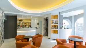 A modern bar area with orange seating and a well-lit interior. - Hotel Biancaneve (Mondolfo)
