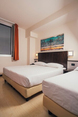 Una habitación de hotel con dos camas, un cuadro en la pared y una ventana con cortinas.