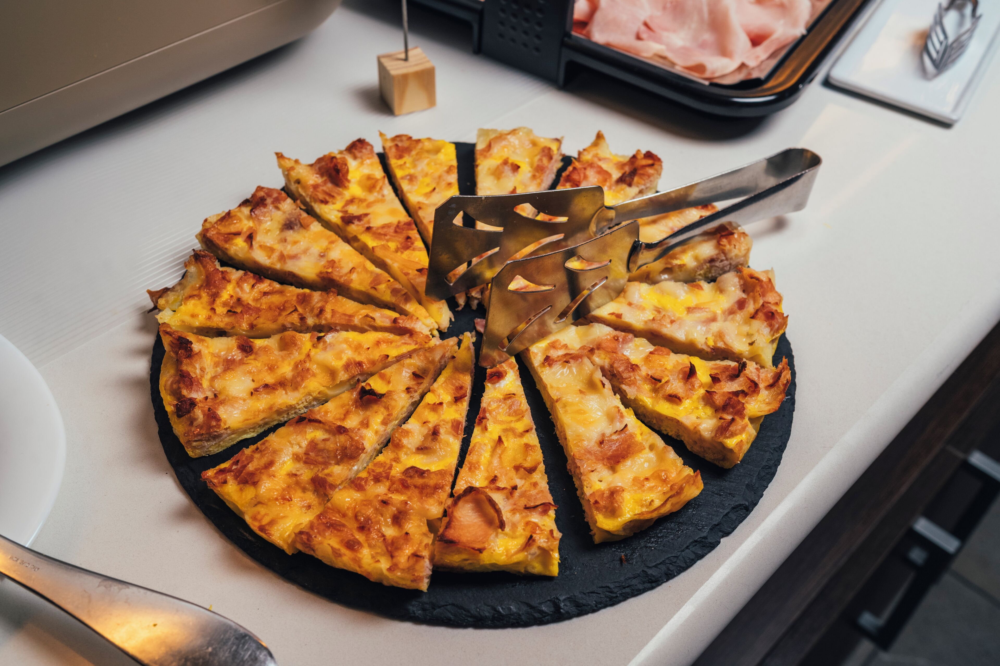 A round black slate plate with a pizza cut into slices.