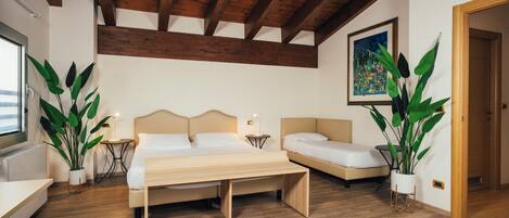 A bedroom with a wooden ceiling, a bed, a bench, and two potted plants.