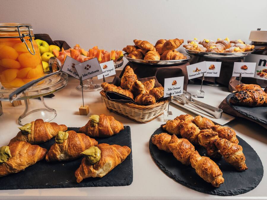A buffet with various food items including pastries, fruits, and a jar of pickled peaches.