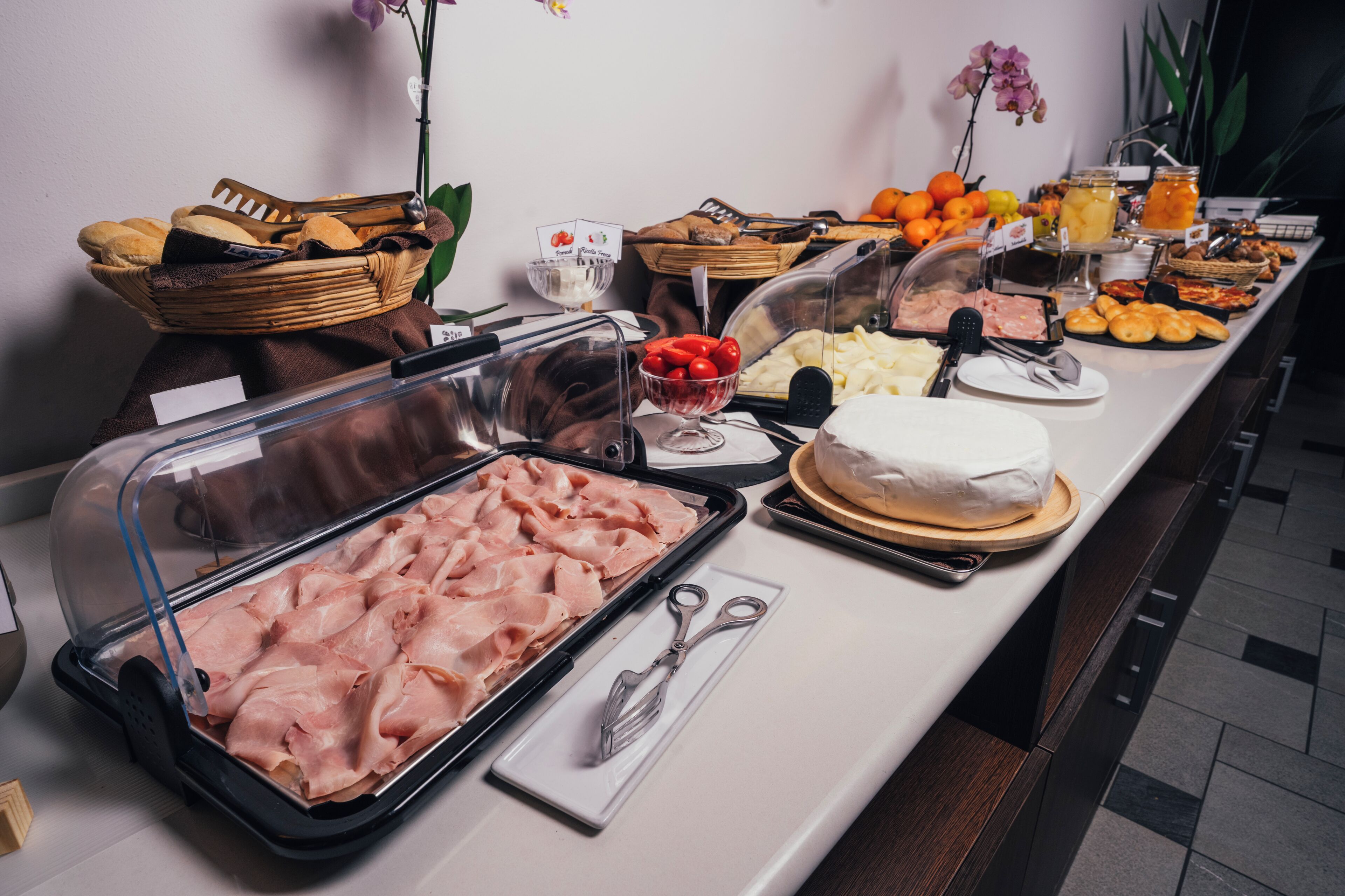 A buffet with various food items including meats, cheeses, fruits, and pastries.