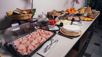 Un bufé con diversas opciones de comida, incluyendo carnes, quesos, frutas y pasteles.