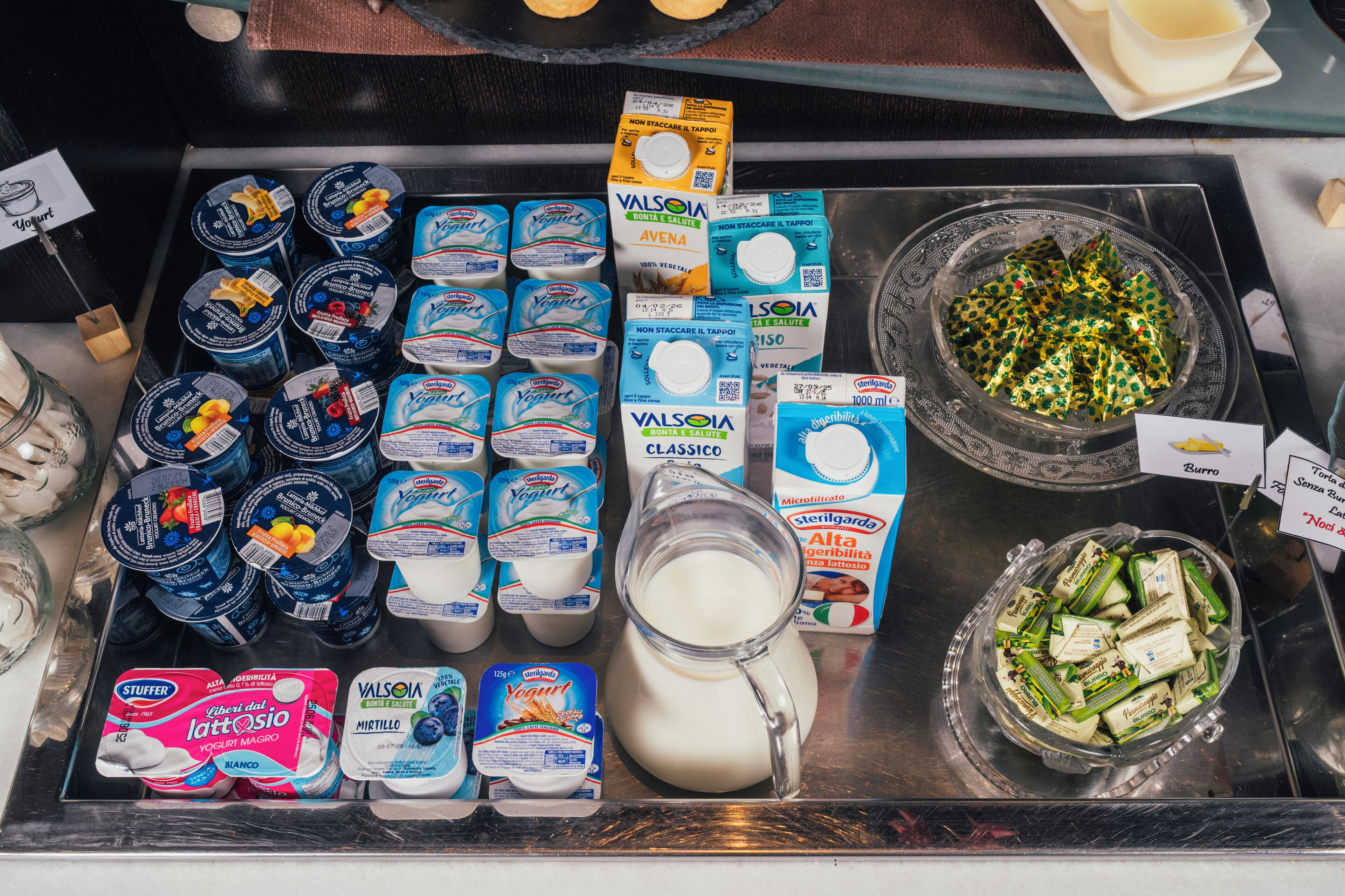 Una selección de productos lácteos, incluyendo varias marcas de yogur y queso, sobre un mostrador de exhibición.